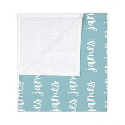 aqua blue swaddle blanket with custom name in white, made out of jersey knit. The design is printed on one side.