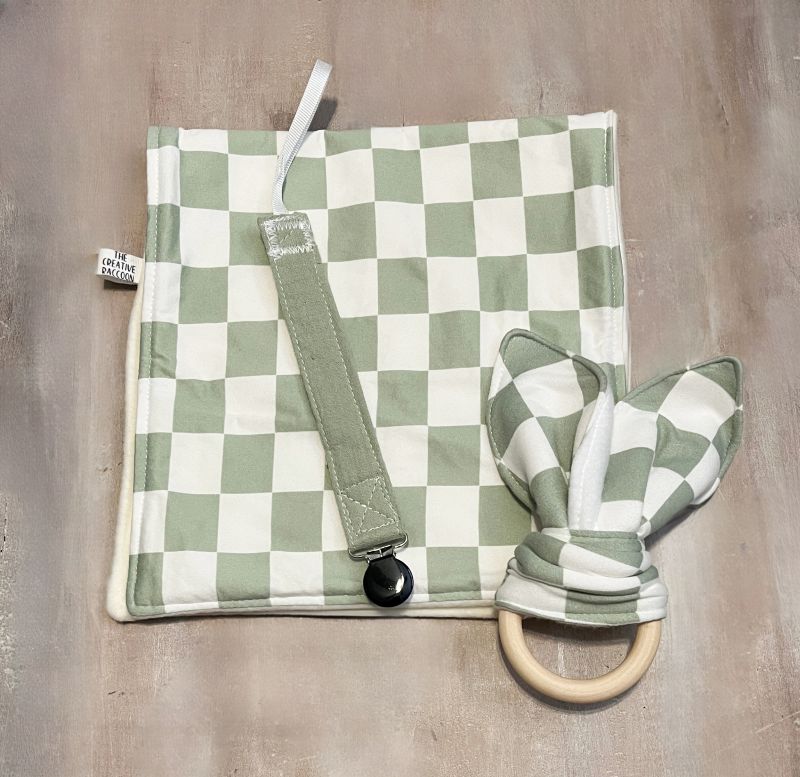 Green and white checkered burp cloth, and teether toy with wooden ring and a green pacifier clip.
Sage Green Checkered Bib and Burp Cloth Set - the Creative Raccoon