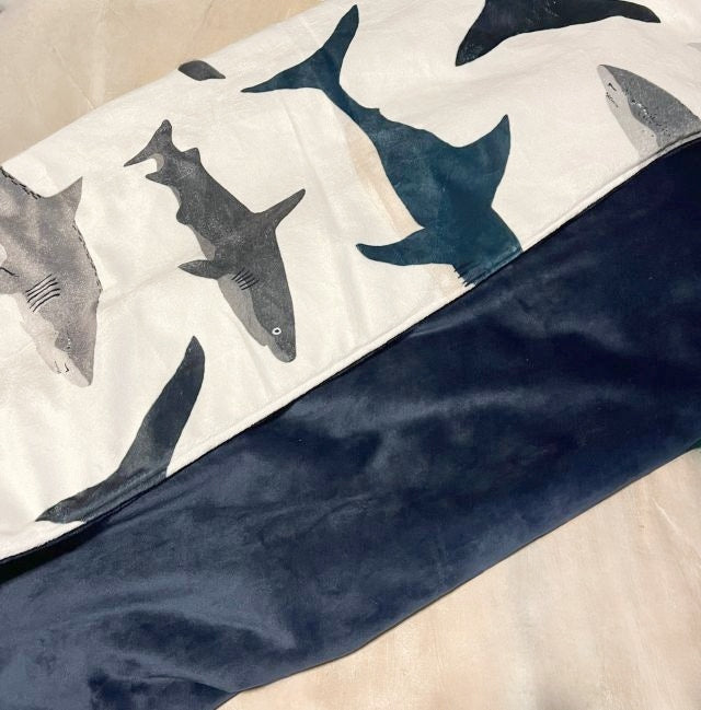 Shark-patterned blanket with a dark blue minky back on a beige background. Shark Nursery Starter Crib Bedding Set - The Creative Raccoon