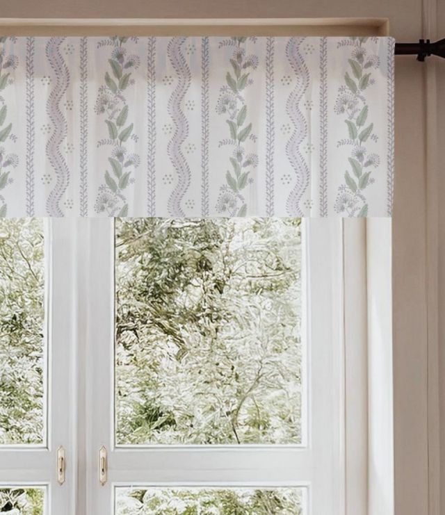 Window with patterned fabric with green leaves and purple flowers on a white background for window valances and a wooden bench with pillows, featuring a view of greenery outside. Window Valance Stripes and Vines, Designer Floral - Pick Your Color - The Creative Raccoon