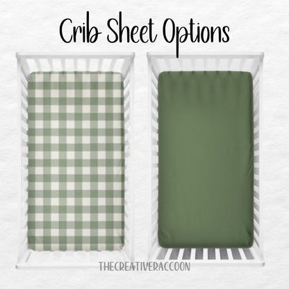 Two crib sheets, one green checkered and one solid green, displayed in a crib. Crib Sheet: Dark Sage Gingham - The Creative Raccoon