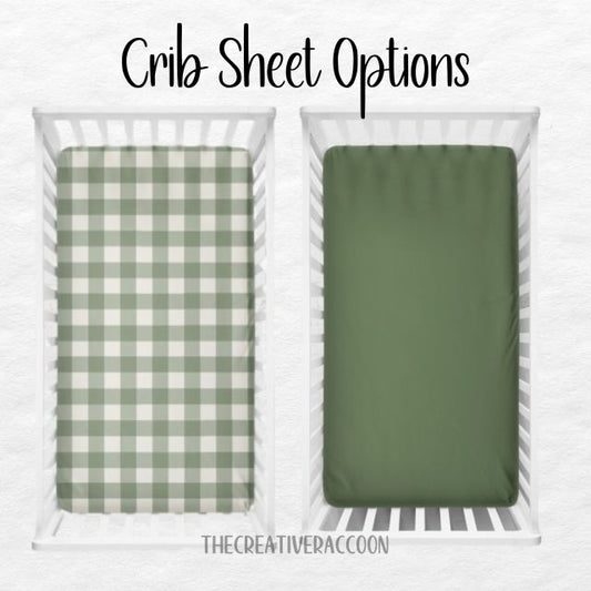 Two crib sheets, one green checkered and one solid green, displayed in a crib. Crib Sheet: Dark Sage Gingham - The Creative Raccoon