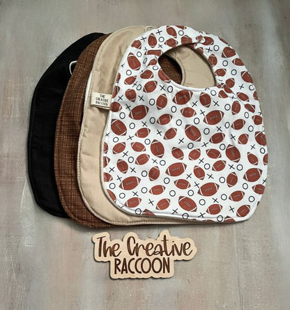 Stack of baby bibs with football pattern, solid black, solid tan, & brown design. Handmade in Kansas, USA. Football Baby Gift Sets, Brown Colors Theme - The Creative Raccoon