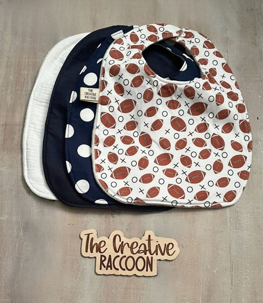 Three baby bibs with different patterns. Solid color bibs - white, & navy blue, patterned baby bibs - football design on white, & navy blue with white dots. Football Baby Gift Sets, Navy Blue Color Theme - The Creative Raccoon