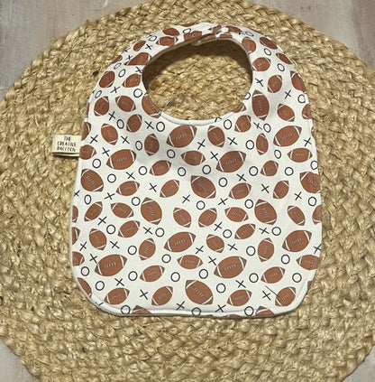 Baby bib with football pattern on a woven mat. football themed baby bibs shown in footballs on a white background. Handmade in Kansas, USA
Football Baby Gift Sets, Kansas Theme - The Creative Raccoon 