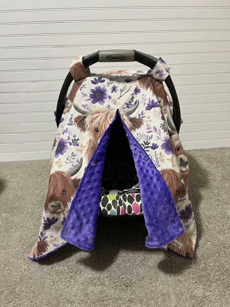 Car seat cover with Highland cow design on a neutral background.
Highland Cow Car Seat Canopy: Farm Floral Nursery Decor - The Creative Raccoon