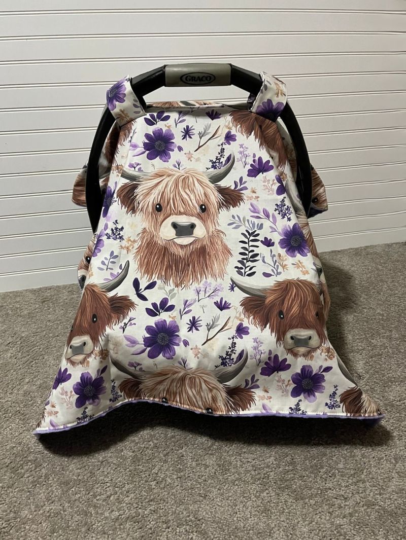 Car seat cover with Highland cow design on a neutral background.
Highland Cow Car Seat Canopy: Farm Floral Nursery Decor - The Creative Raccoon