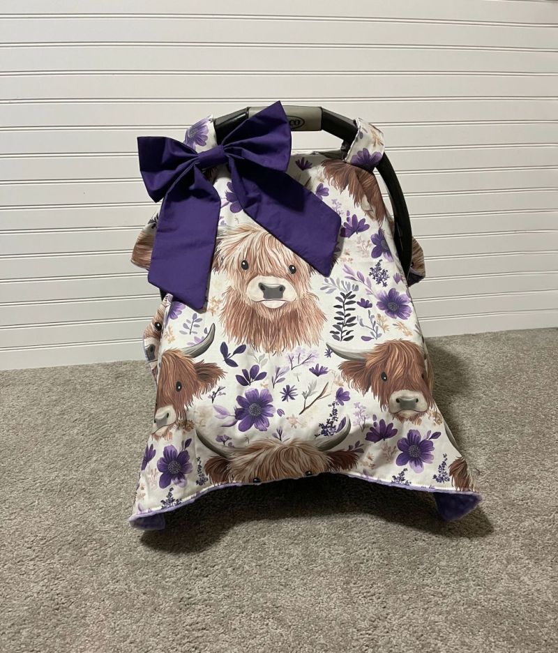 Car seat cover with Highland cow design on a neutral background.
Highland Cow Car Seat Canopy: Farm Floral Nursery Decor - The Creative Raccoon