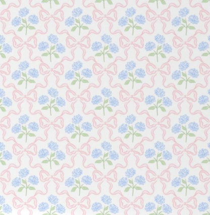 Floral-patterned crib sheet with pink and blue Hydrangeas and Bows flowers on a white crib. Hydrangeas and Bows Crib Sheet - The Creative Raccoon
