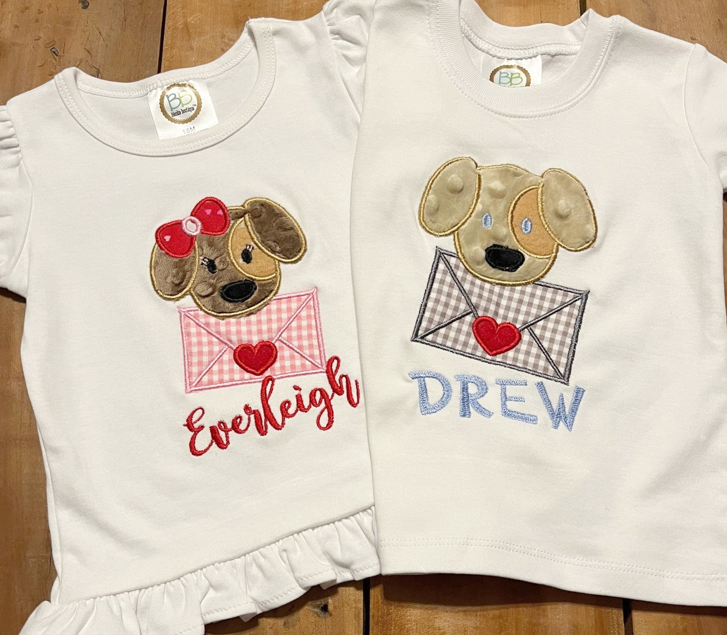 Girl dog Valentine's Day Shirt, embroidered design of a puppy holding an envelope and personalized with child's name. Name shown in Everleigh font. Boy Puppy shirt name shown in carson font