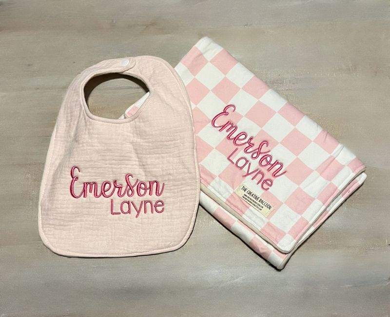 Baby bib and checkered burp cloth with 'Emerson Layne' branding on a wooden surface
Pink Checkered Baby Bib and Burp Cloth Personalized
