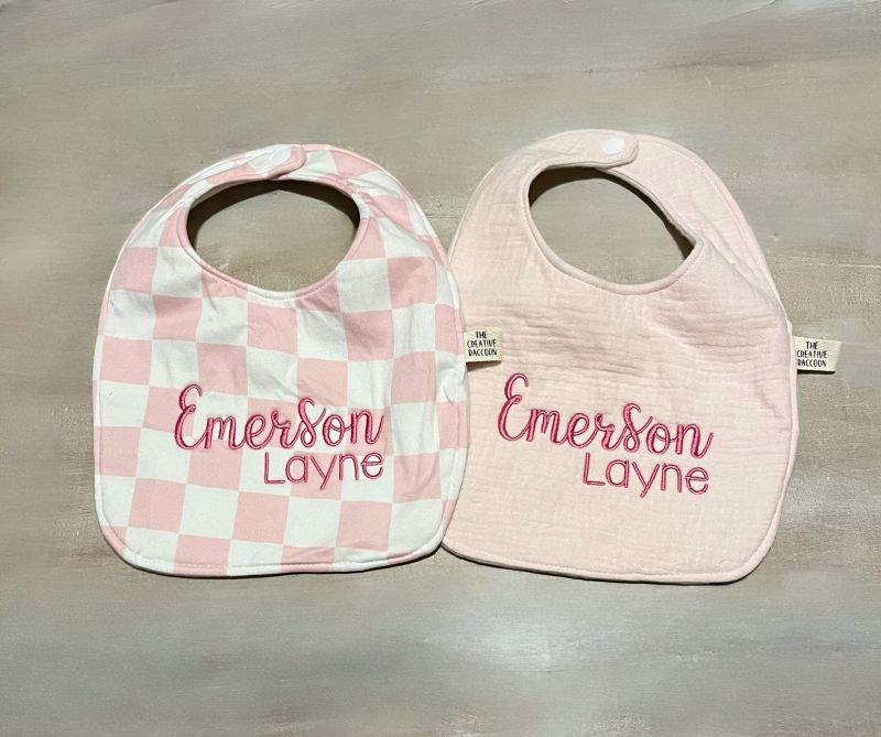 Two baby bibs with 'Emerson Layne' embroidery on a gray background
Pink Checkered Baby Bib and Burp Cloth Personalized