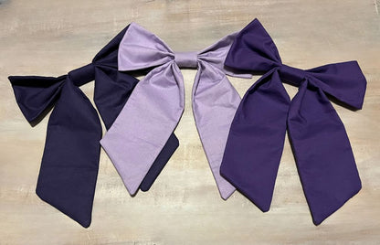 Three large fabric bows in purple and lavender on a wooden surface. Purple bow add-ons for car seat canopy or crib decor. - The Creative Raccoon