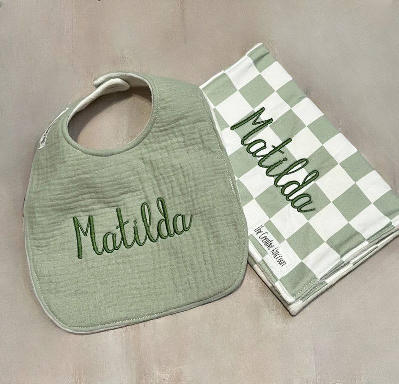 Green bib and checkered burp cloth with 'Matilda' embroidery on a beige background. Sage Green Checkered Bib and Burp Cloth Set - the Creative Raccoon