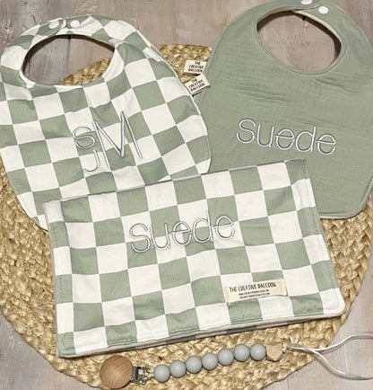 green checkered bib and burp cloth with additional green bib with 'Suede & SJM' embroidered on all items.
Sage Green Checkered Bib and Burp Cloth Set - the Creative Raccoon