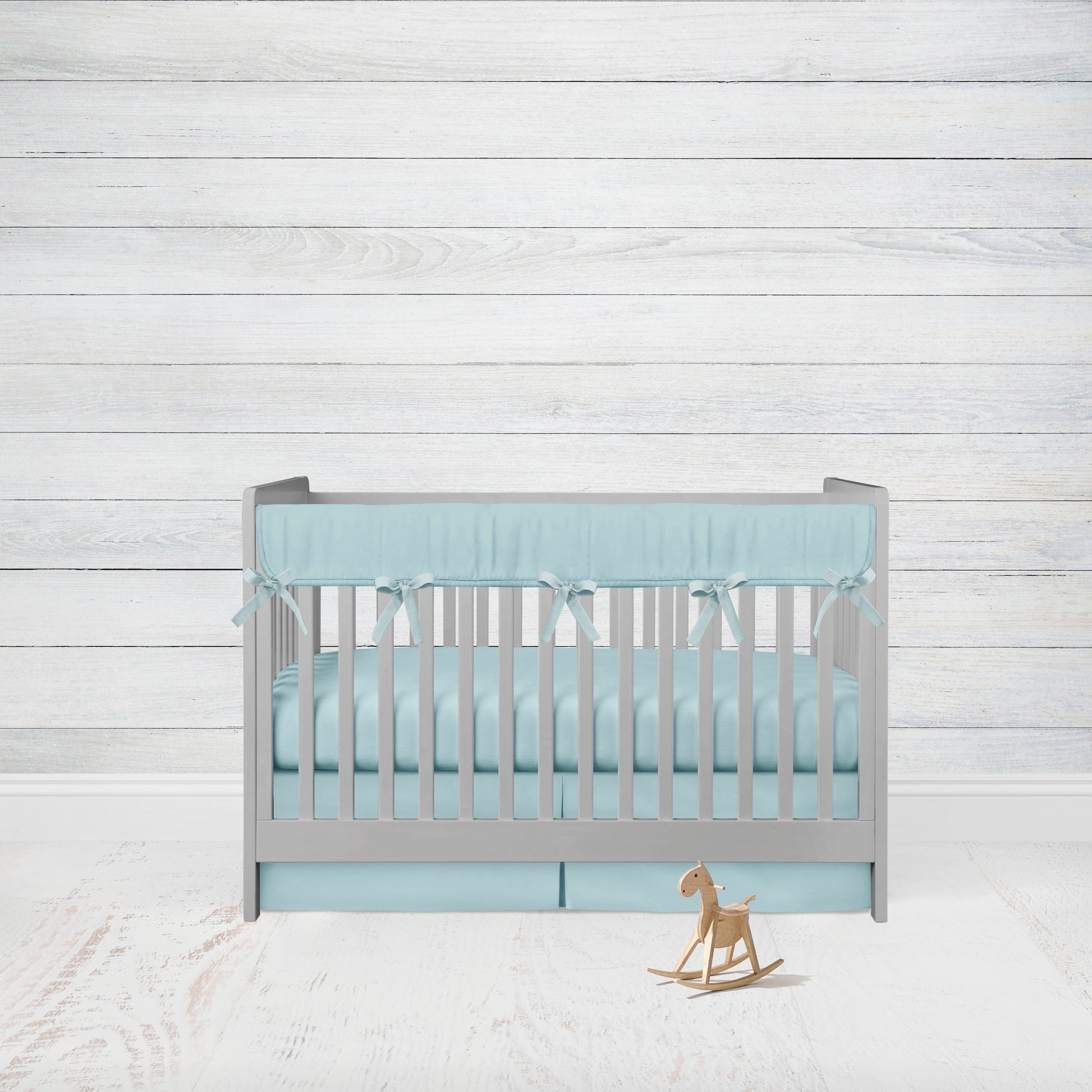 aqua crib rail cover with aqua ties, aqua crib sheet & aqua pleat crib skirt shown on a crib in a nursery