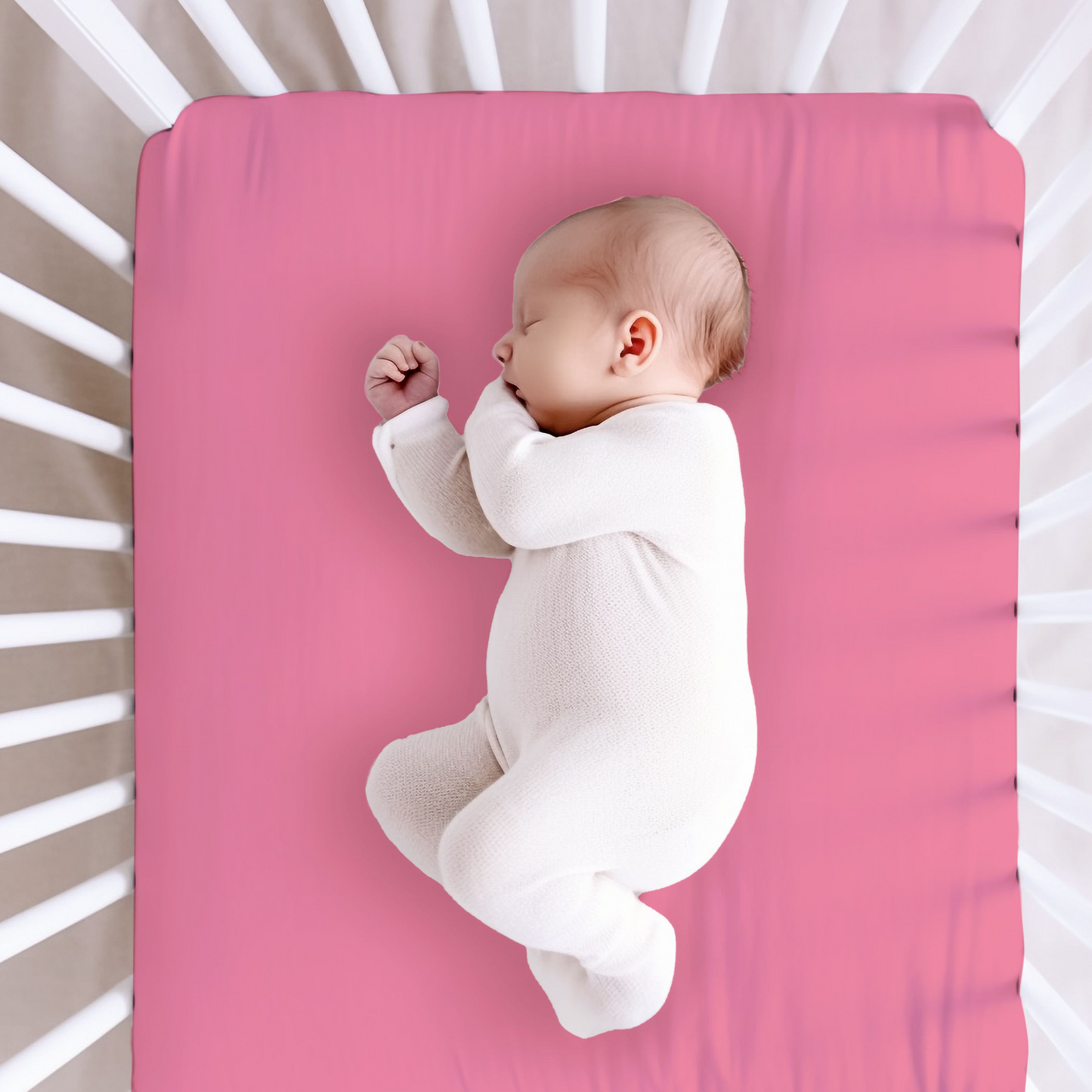 hot pink crib sheet shown with a baby in a crib.