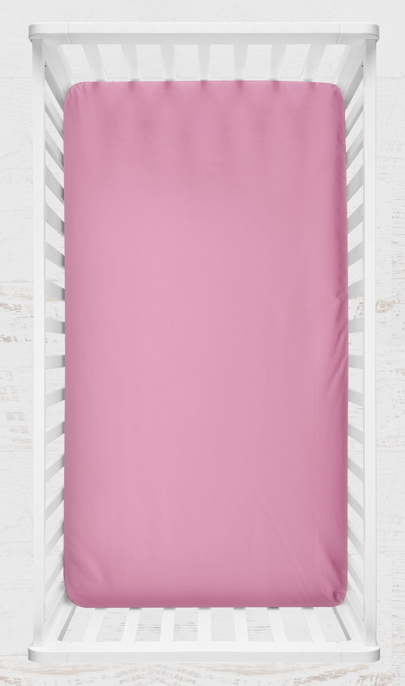 pink crib sheet shown on a crib