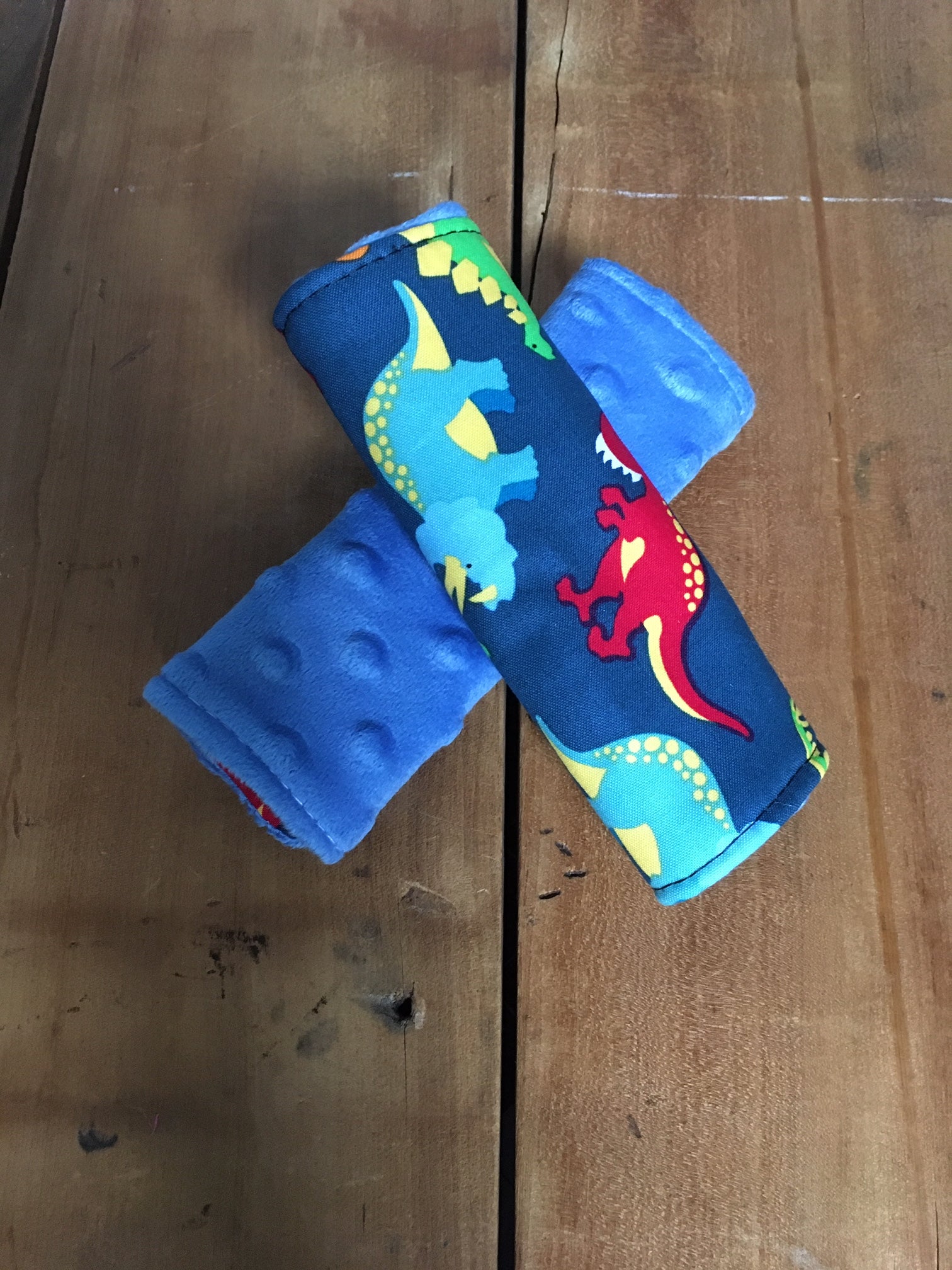 navy dinosaur car seat strap covers - dinosaurs in light blue, orange, red and green shown in 6" size shown with blue minky