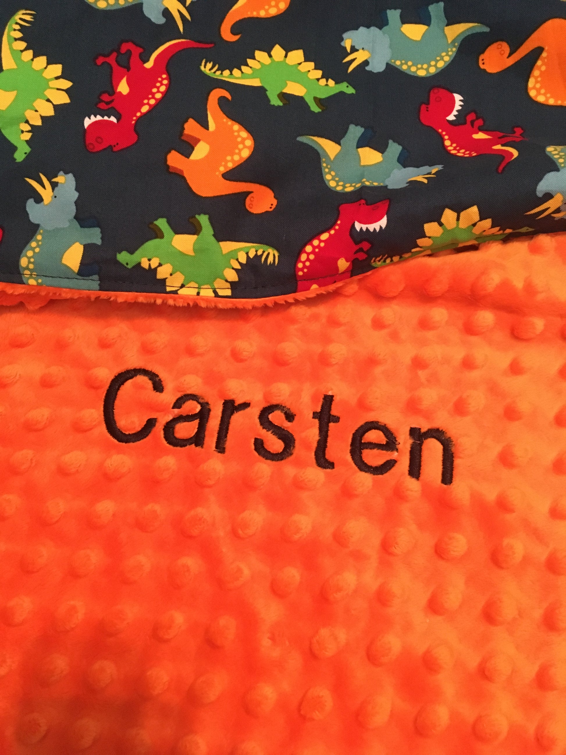 "Carsten" name embroidered on a dino minky blanket