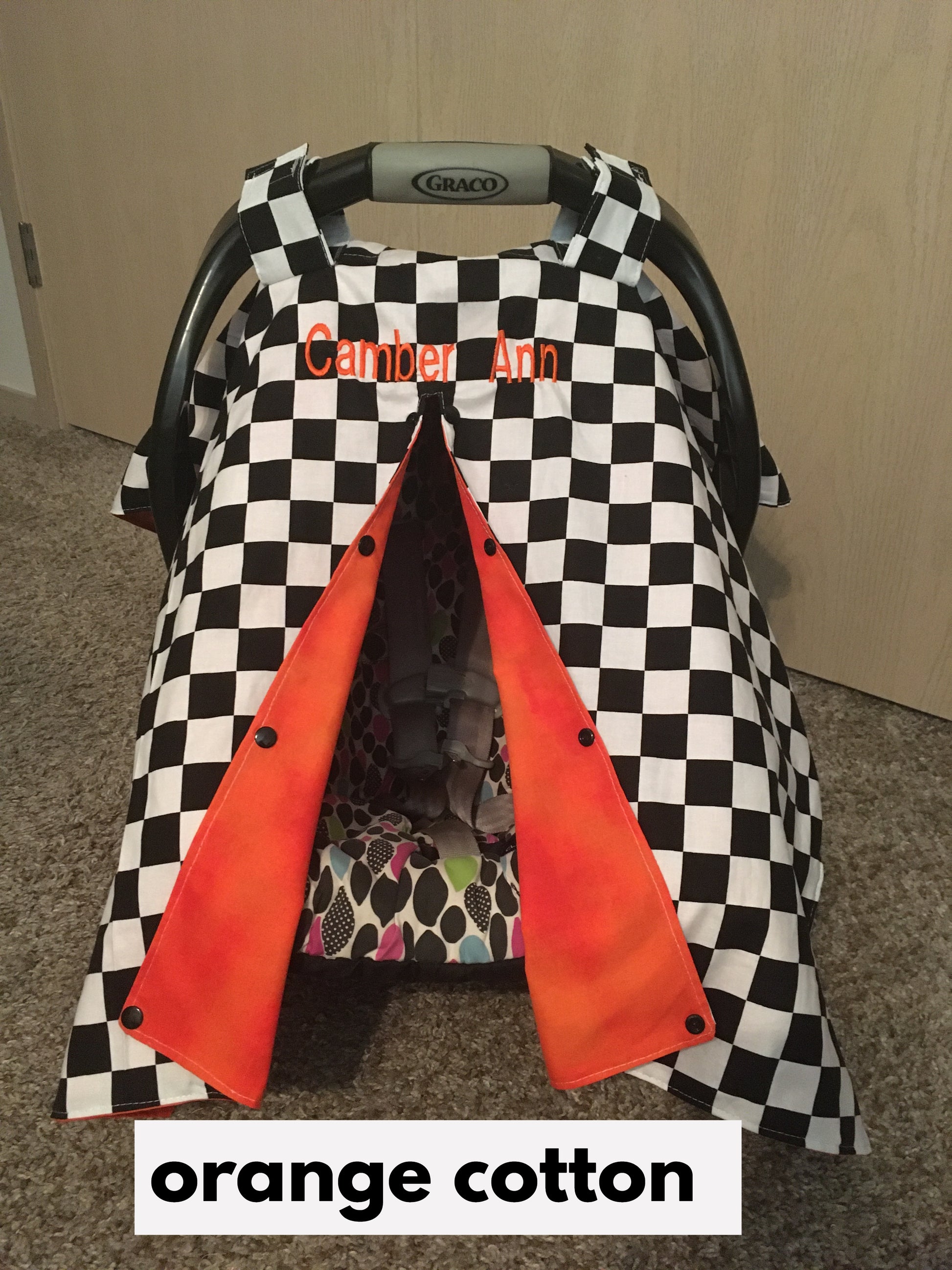 racing check car seat canopy shown in orange cotton, in the open option, shown with name (additional fee)