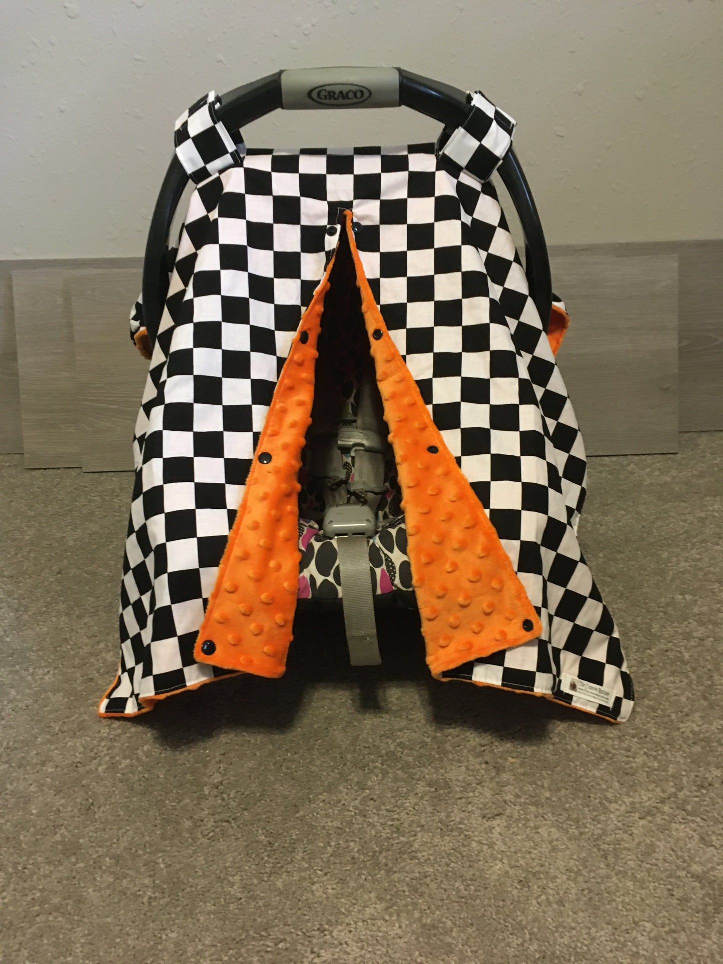 racing check car seat canopy shown in orange minky, in the open option