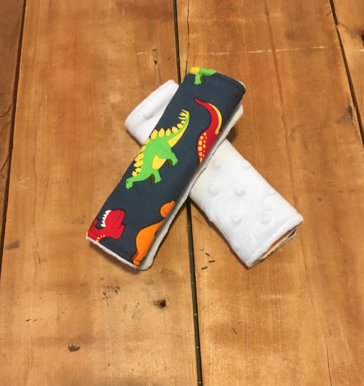 navy dinosaur car seat strap covers - dinosaurs in light blue, orange, red and green shown in 6" size shown with light blue minky