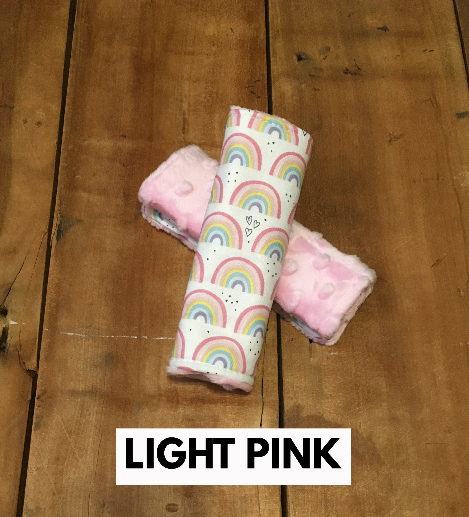 Rainbow car seat strap covers shown in the 6" size with light pink minky back