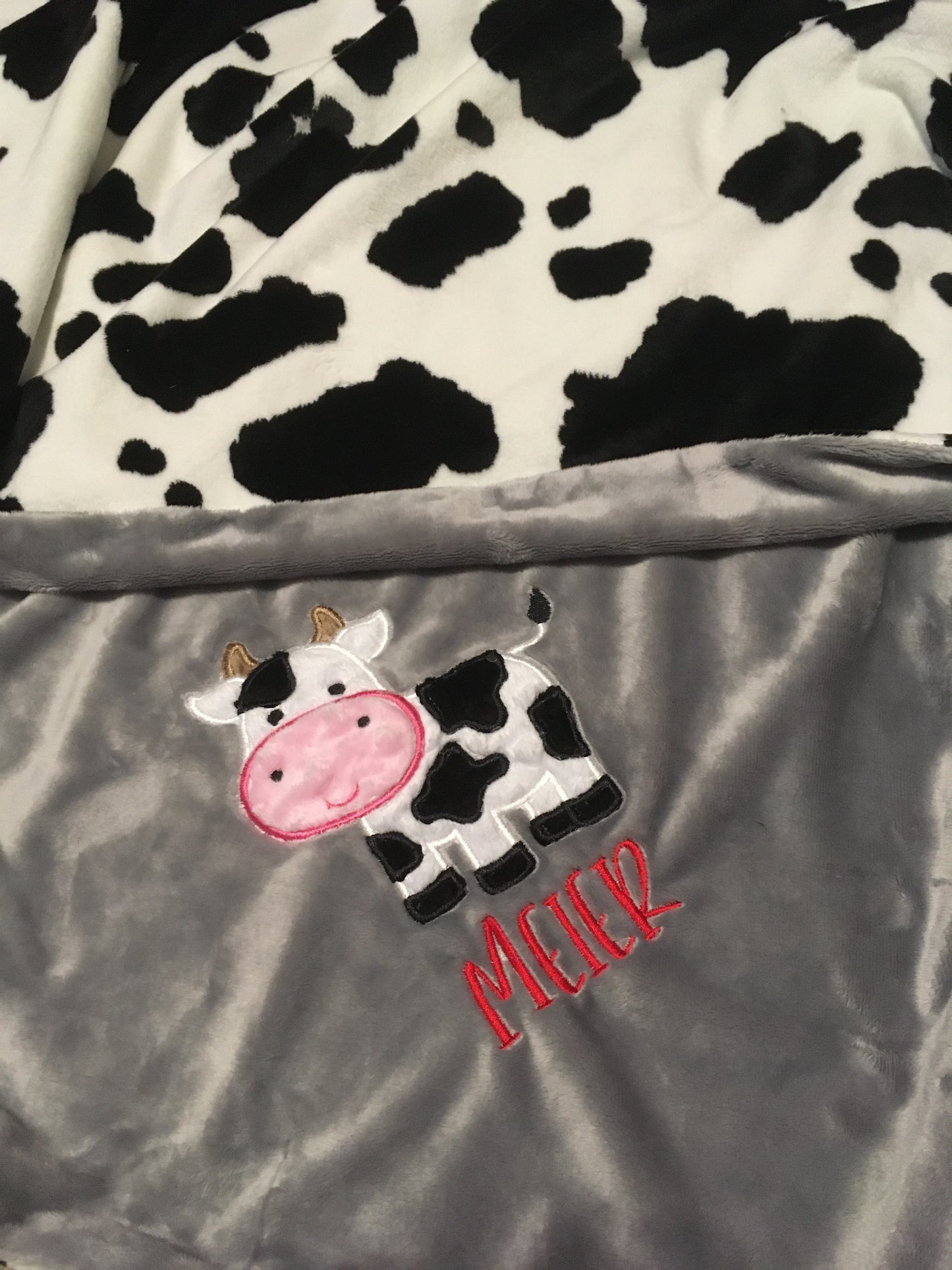Black and white cow applique with name on a gray minky for a cow blanket