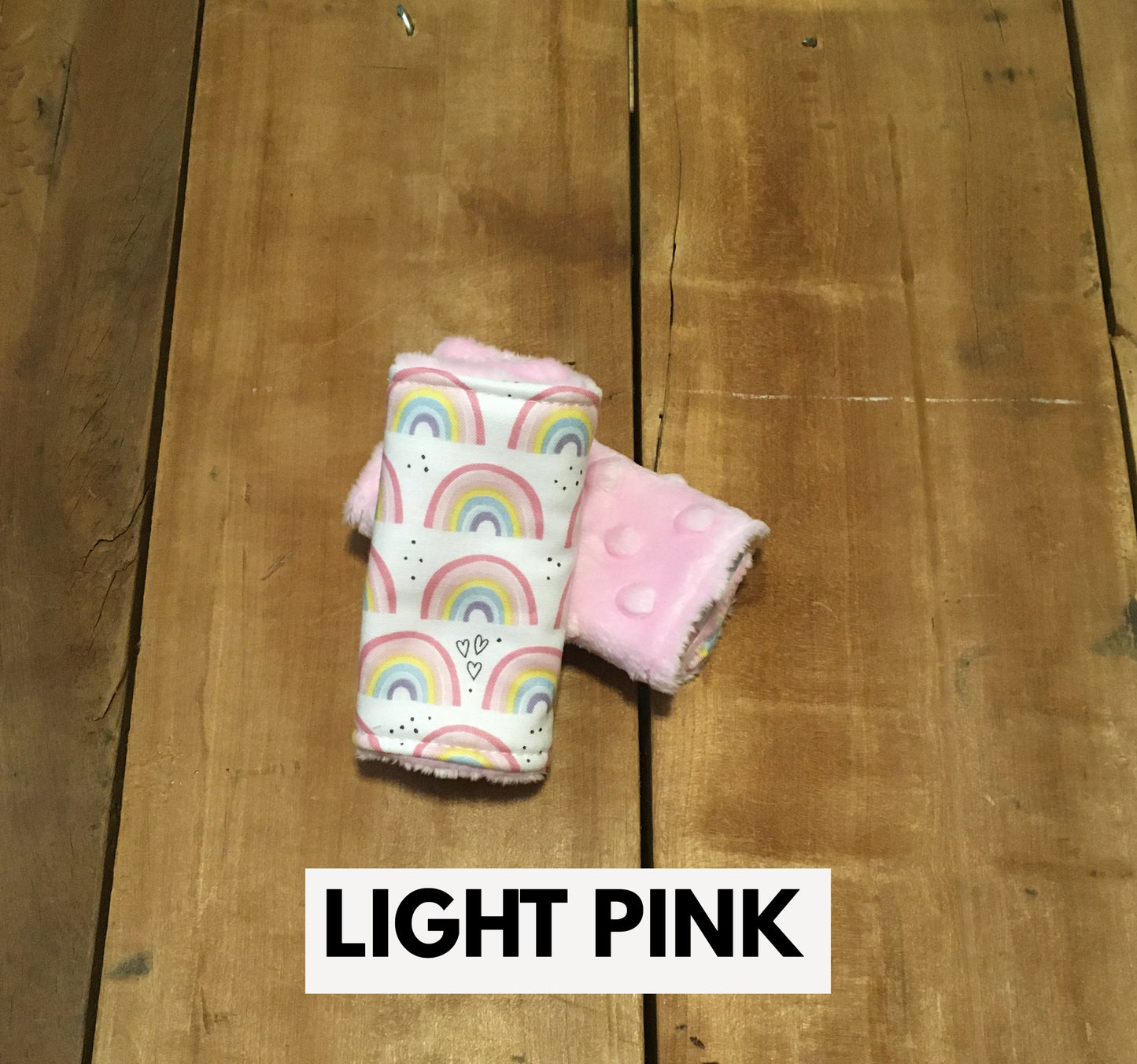 Rainbow car seat strap covers shown in the 4" size with light pink minky back