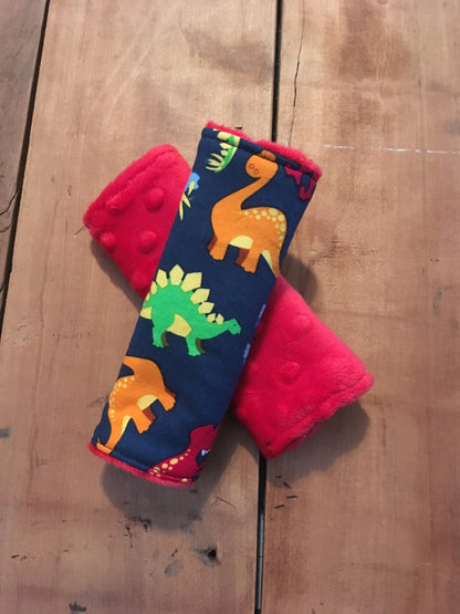navy dinosaur car seat strap covers - dinosaurs in light blue, orange, red and green shown in 6" size shown with red minky