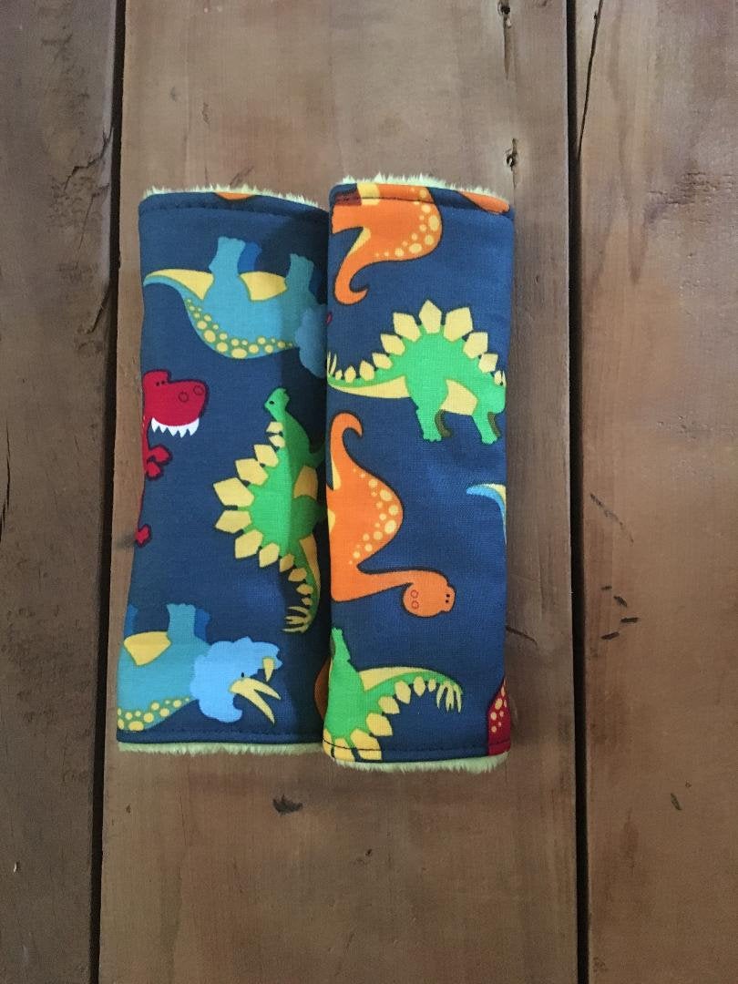 navy dinosaur car seat strap covers - dinosaurs in light blue, orange, red and green shown in 6" size