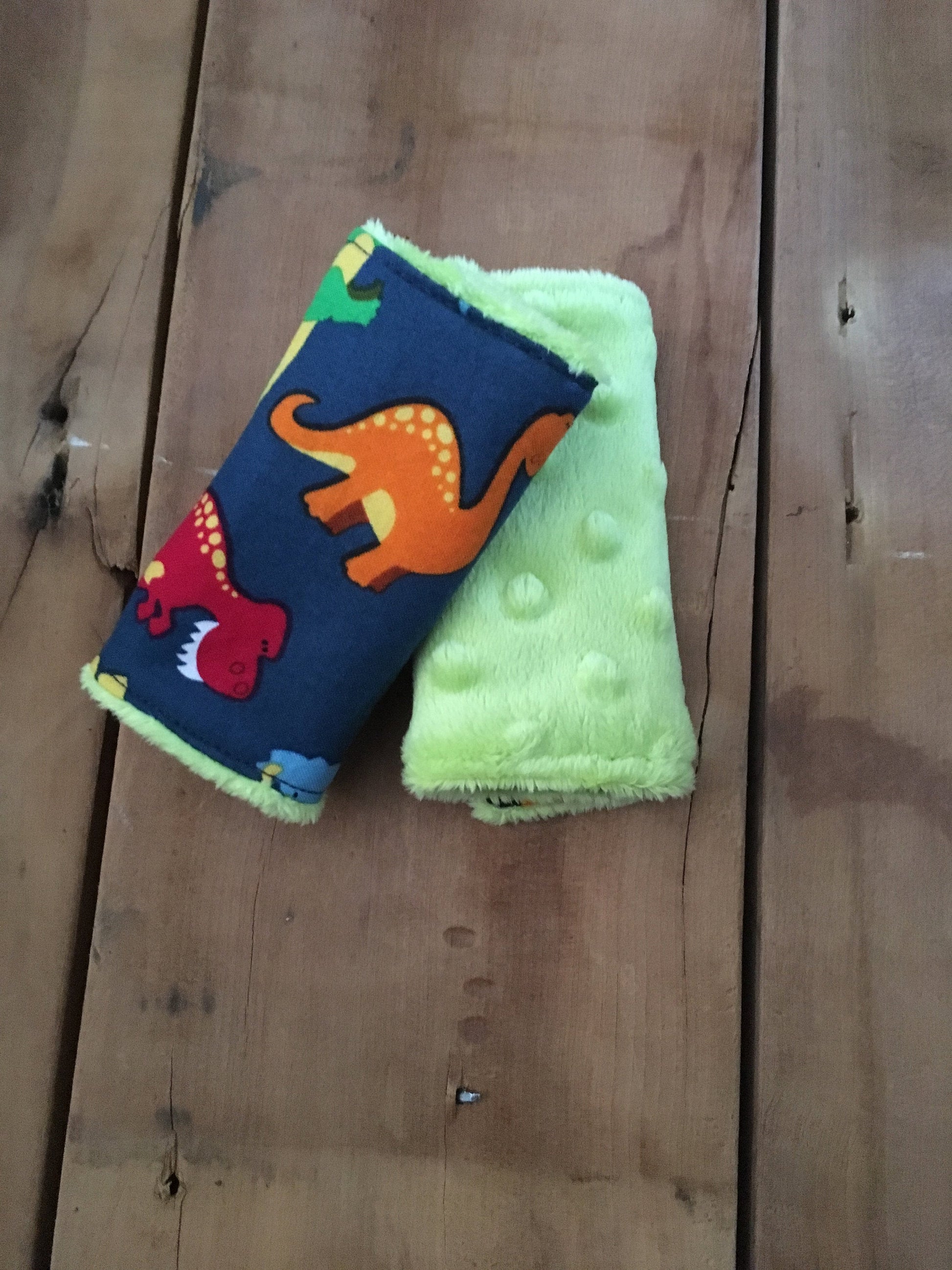 navy dinosaur car seat strap covers - dinosaurs in light blue, orange, red and green shown in 4" size shown with lime green minky