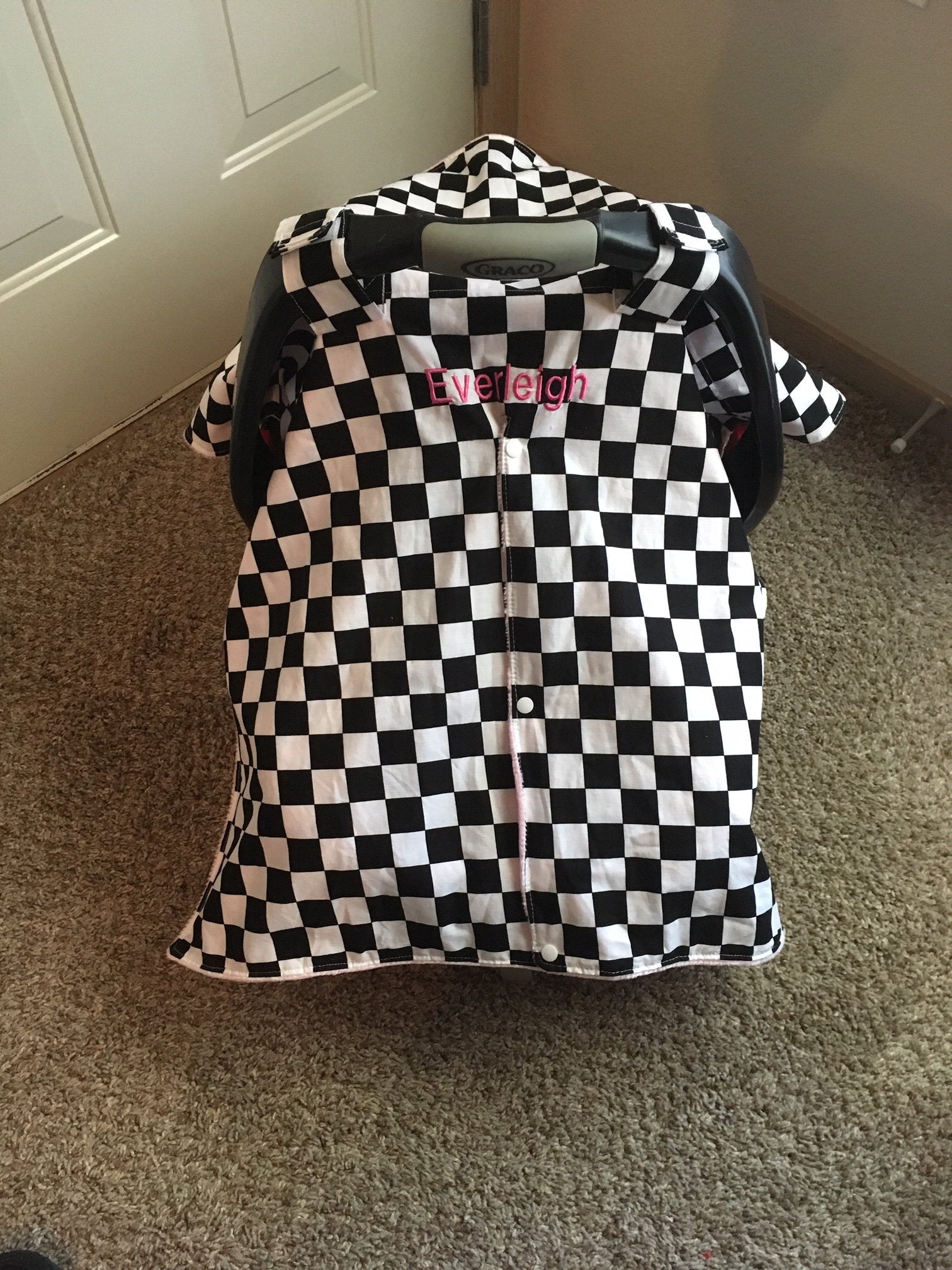racing check car seat canopy shown in light pink minky, in the open option, shown with a name (additional fee)