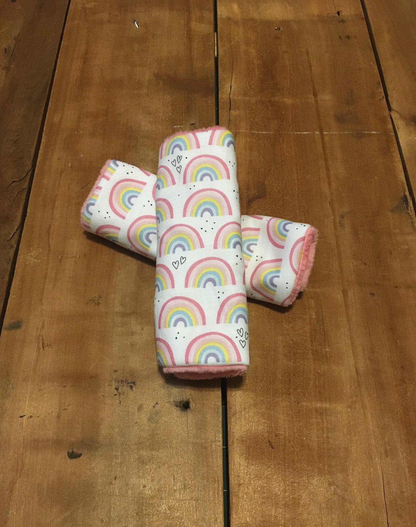 Rainbow car seat strap covers shown in the 6" size with coral minky back