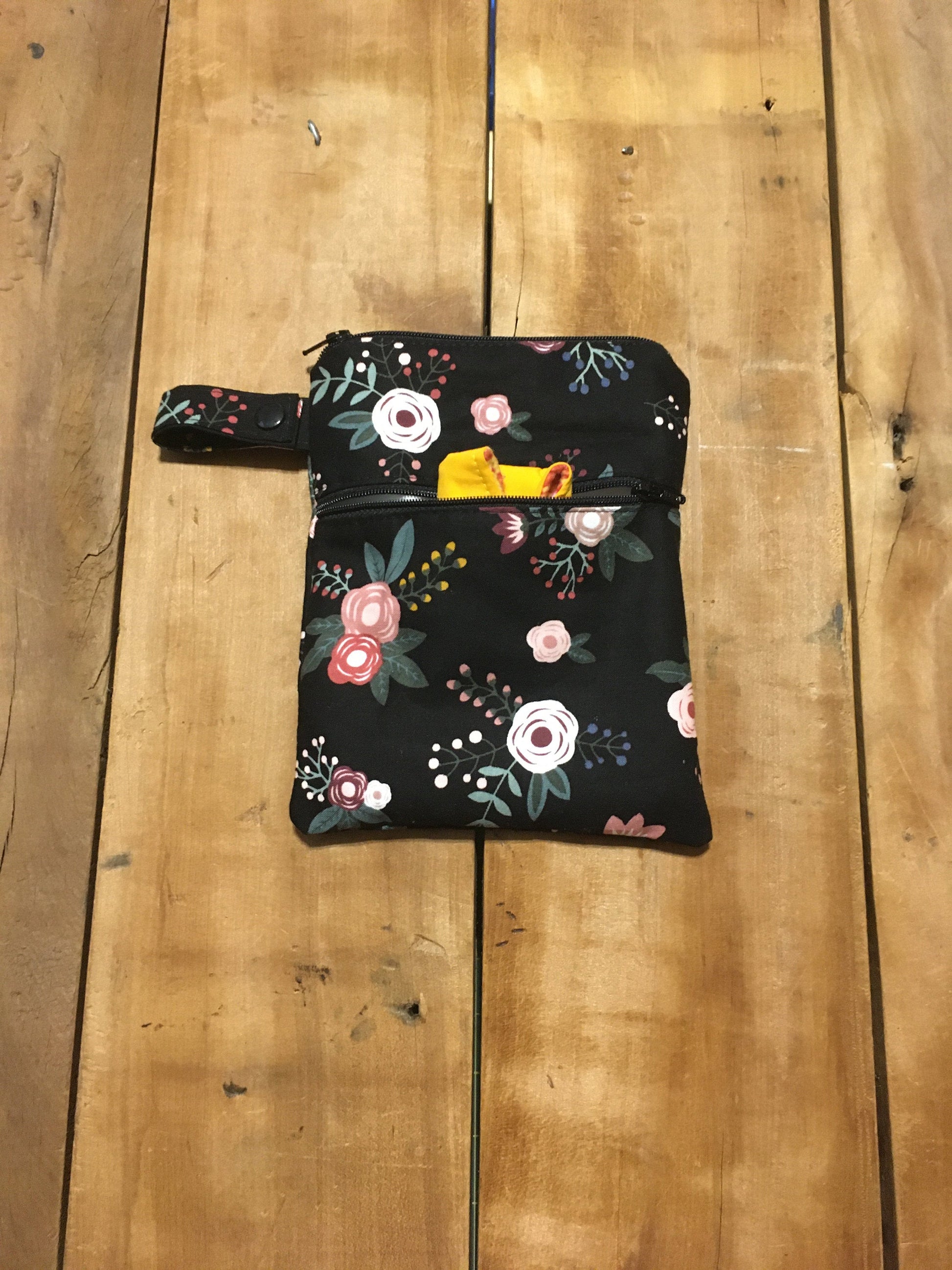 black floral wet dry bag with wet top pocket and dry front pocket, shown with strap