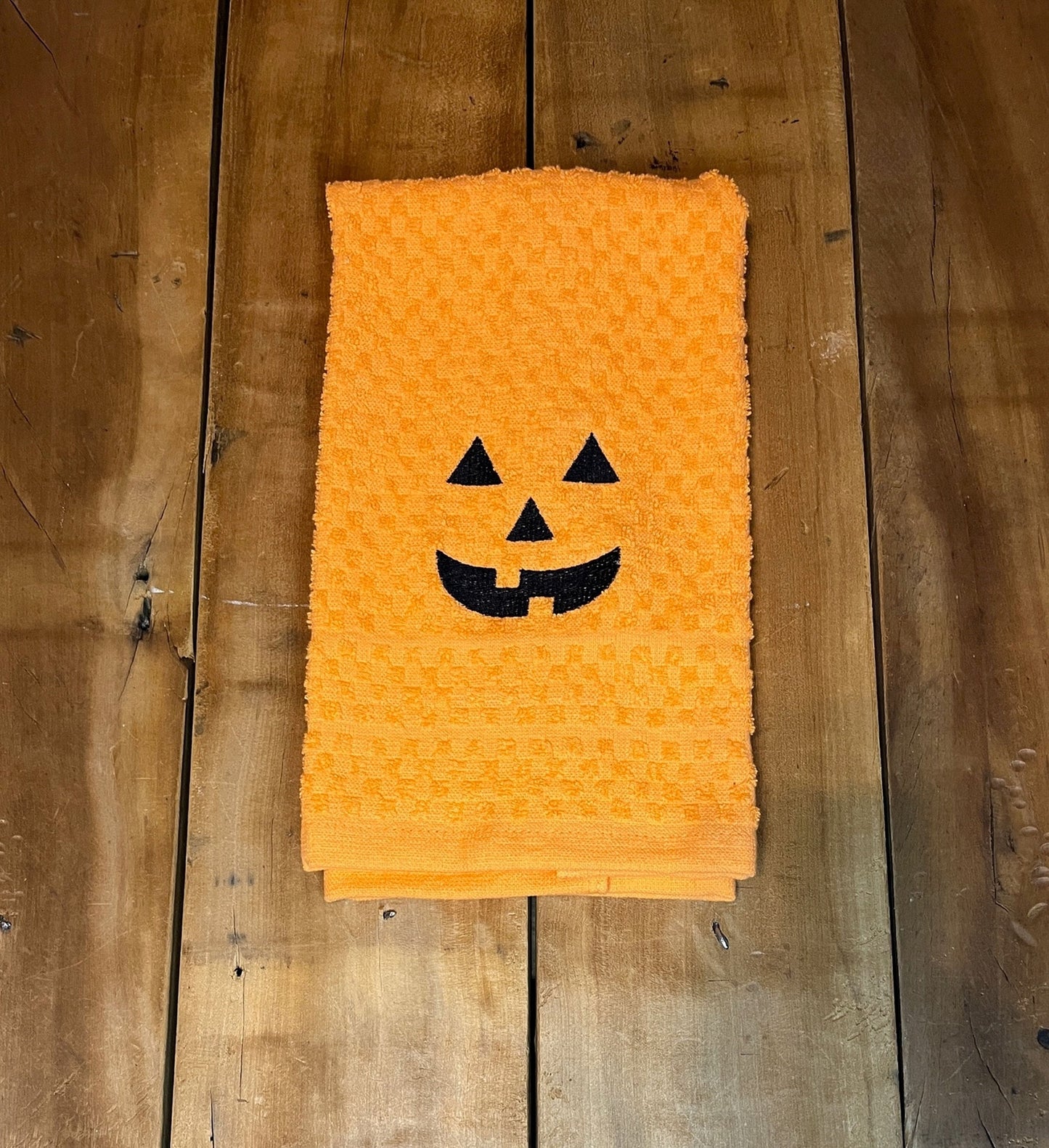 orange towel with pumpkin face embroidered on them
