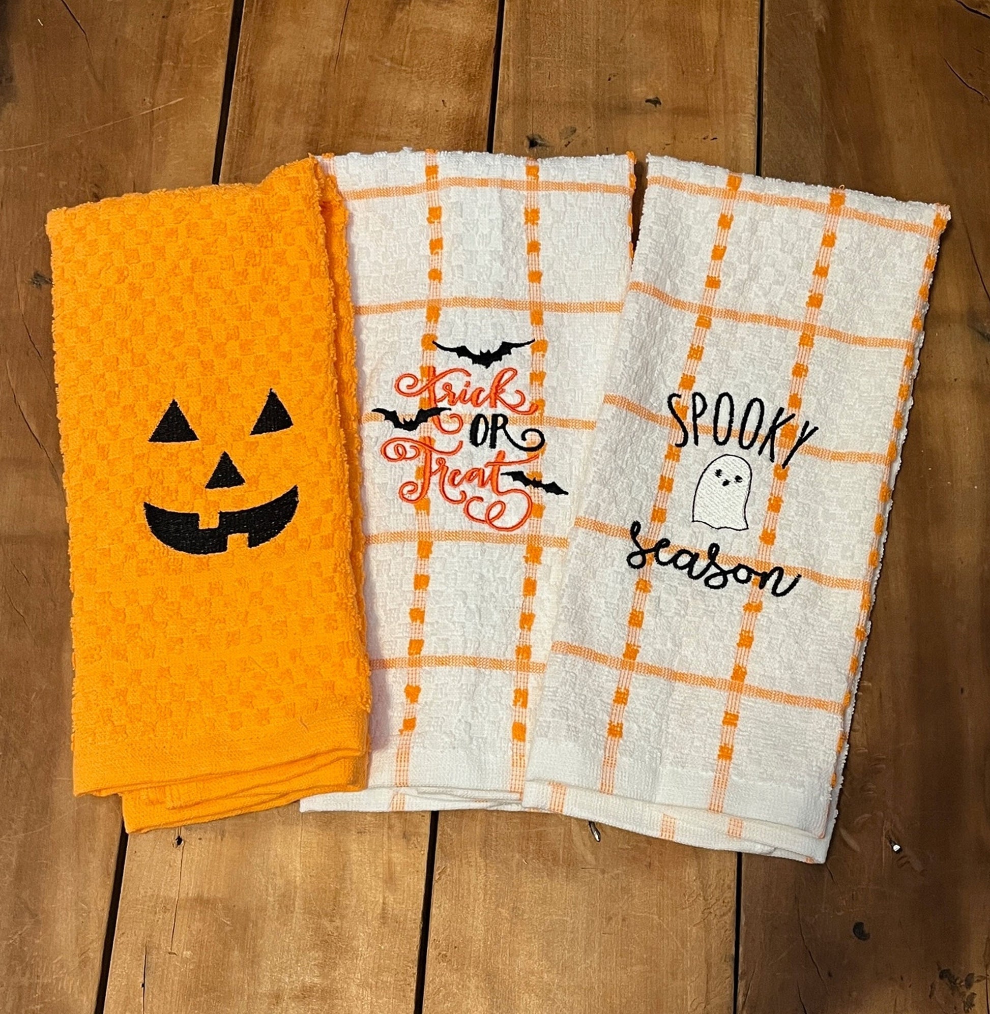 orange towel with pumpkin face, orange and white stripe towels trick or treat, spooky season embroidered on them