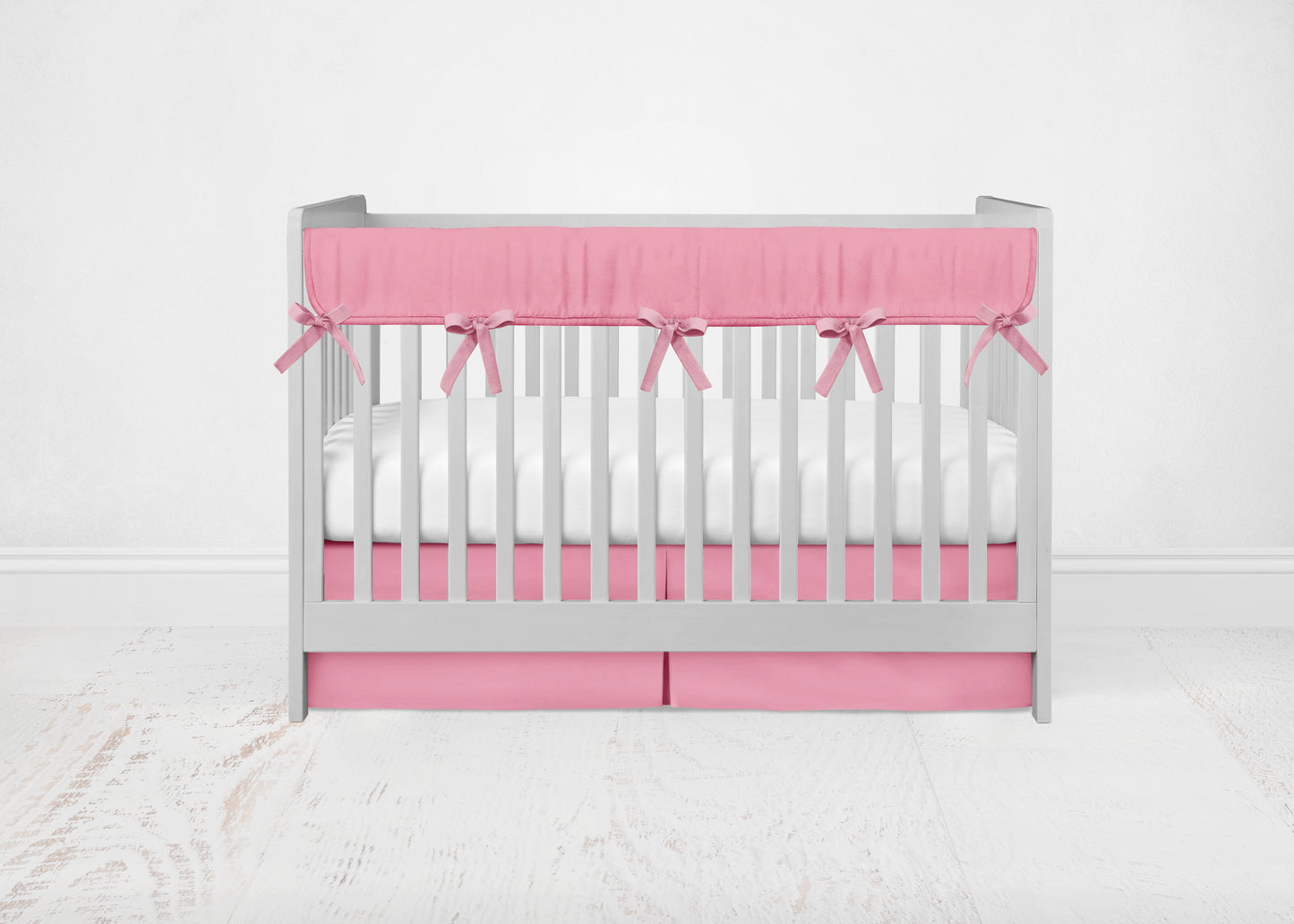 solid hot pink crib rail cover, pleat skirt shown on a crib